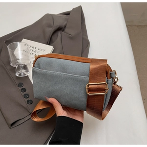 Detailed close-up of grey canvas small square crossbody bag with brown nylon strap