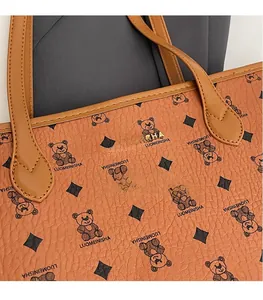 Macro shot of grainy leather tote bag with bear monogram pattern and gold metal logo