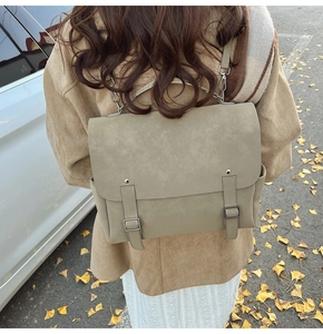 Outdoor lifestyle shot of a vintage khaki suede backpack with decorative buckle straps