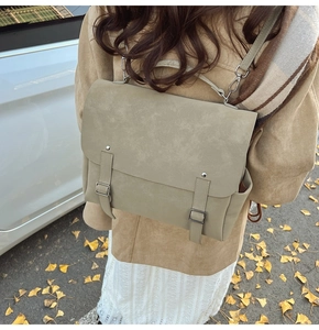 Outdoor shot of a beige matte leather satchel backpack with vintage metal buckles