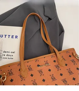 Detail of a brown leather tote bag showing vintage bear prints and metal logo accent