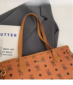 Detailed close-up of brown leather tote bag with bear motifs and gold metal hardware hooks