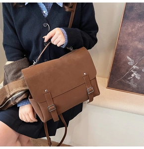 Detailed side view of a large brown vintage messenger bag with metal buckles and handle