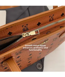 Detailed macro of smooth gold-tone zipper head on brown bear monogram leather tote bag