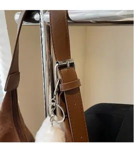 Detail of adjustable brown leather shoulder strap with silver buckle and plush charm