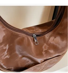 Detail view of smooth silver metal zipper and brown textured leather on tote bag