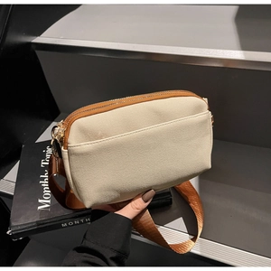 Detail of canvas crossbody bag with dual zip pockets and adjustable brown fabric strap