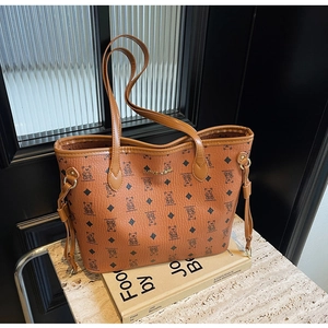 Detail of large brown tote bag with bear print pattern and golden logo on stone surface