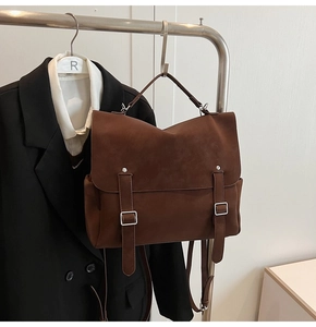 Close-up of a dark brown matte leather backpack with silver buckles on a display