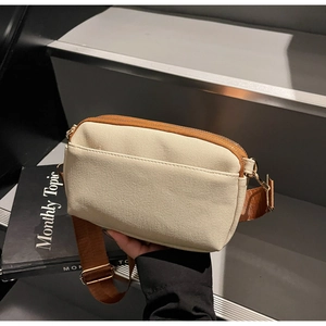 Detail of canvas crossbody bag with double zipper compartments and adjustable strap