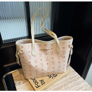 Close-up of cream tote bag featuring bear prints and a gold engraved brand plate