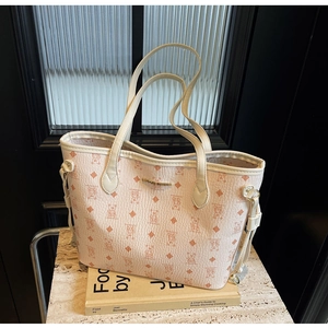 Macro view of beige tote bag with bear pattern embossing and gold brand plaque detail