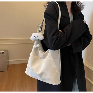 Detail of a large cream tote bag featuring a cute white cloud plush pendant accessory