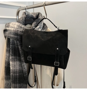 Detail of matte black messenger bag with silver buckles and flap design on a hanger