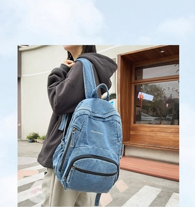 Detalle de la mochila de mezclilla lavada con letras blancas y correas cómodas