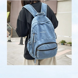 Detalle de la tela denim lavada azul duradera y los bolsillos con cremallera en la mochila
