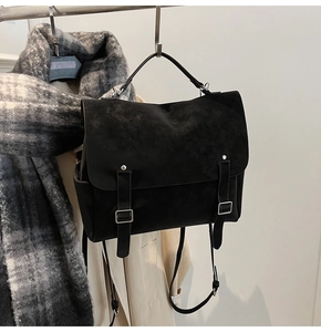 Detail of black matte dual-buckle backpack hanging with a scarf in a minimalist setting