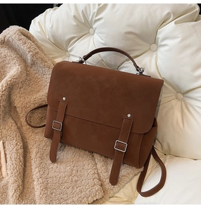 Close-up of brown frosted leather backpack with dual metallic buckles and retro handle