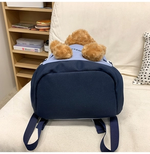 Close-up of navy blue and light blue backpack featuring a cute 3D plush bear on top
