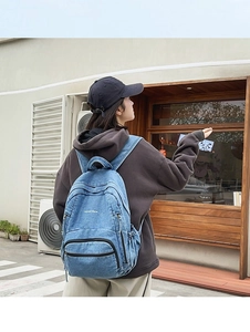 Vista exterior de una mochila de mezclilla azul desgastada llevada por una modelo casual