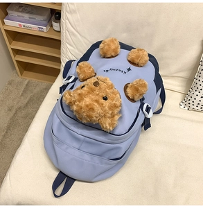 Detail view of a light blue nylon backpack featuring a 3D plush brown bear mascot