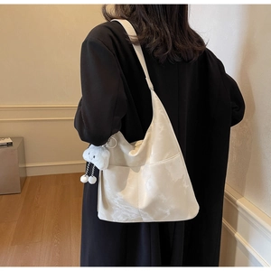 Detail of a large cream tote bag with marble pattern and plush cloud charm on a model