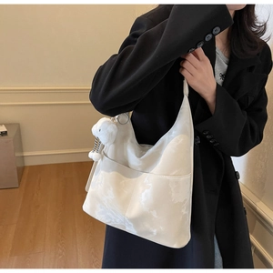 Detail of white marble texture tote bag with plush rabbit charm on black blazer