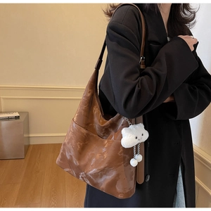 Brown faux leather large tote bag shown on shoulder with plush cloud charm detail