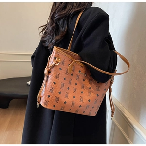 Detail view of brown faux leather tote bag with bear pattern and metal logo