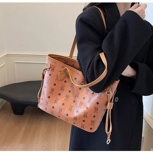 Detail of lychee textured leather tote bag with bear pattern and gold metal logo