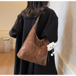Brown glossy tote bag shown from behind on a model with a cute plush cloud charm
