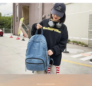 Mochila de mezclilla azul lavado con bolsillos de cremallera en un entorno urbano