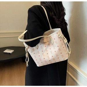 Detailed view of cream tote bag with bear print, gold logo, and side drawstring accents