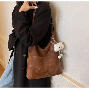 Detail view of large dark brown leather tote bag with cloud charm on female model