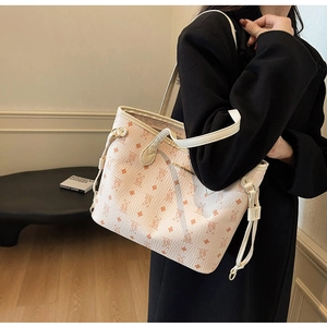 Detail of pink monogrammed tote bag with cartoon bear pattern and gold logo detail