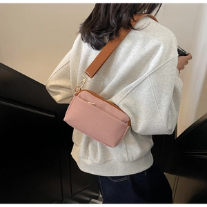 Detail of cherry pink canvas crossbody bag with brown wide strap on female model