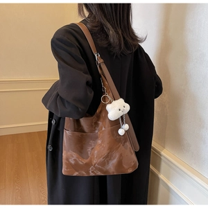 Detail of brown faux leather tote bag with side pocket and white cloud plush charm