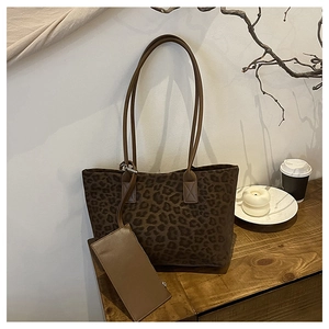 Leopard print suede tote bag with matching pouch shown on a wooden table setup
