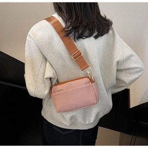 Detail of pink crossbody bag with brown adjustable strap shown on model's shoulder