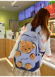 Detail of cute brown teddy bear plush attached to a purple student backpack