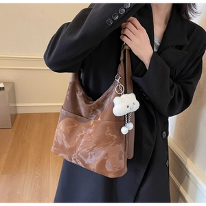 Detail of deep brown marble texture tote bag with a white plush cloud charm accessory