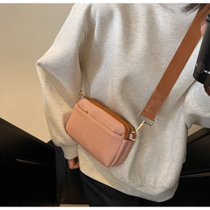 Detail view of pink and brown crossbody bag with multi-zipper layers and wide strap