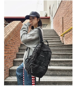 Mochila vintage de lona lavada negra con múltiples bolsillos mostrada en exteriores