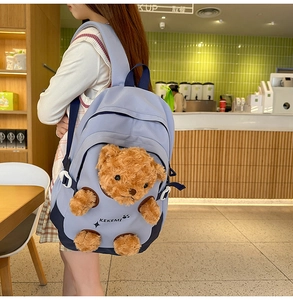 Detail of cute purple canvas backpack featuring a 3D plush teddy bear and blue straps