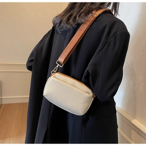 Minimalist beige canvas crossbody bag with brown woven strap shown on person