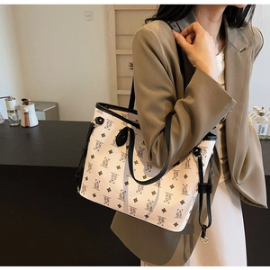 Detail of bear pattern tote bag featuring litchi texture and black leather handles