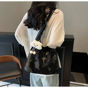 Detail of glossy black tote bag with plush cloud charm and wide shoulder strap