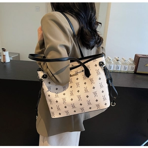 Detail of off-white tote bag with bear print and black leather trim worn by model