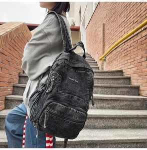 Vista detallada de mochila de mezclilla lavada con varios bolsillos con cremallera