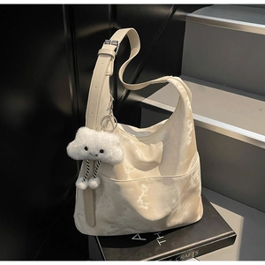 Detail of off-white hobo bag with marble texture and white cloud plush charm accessory